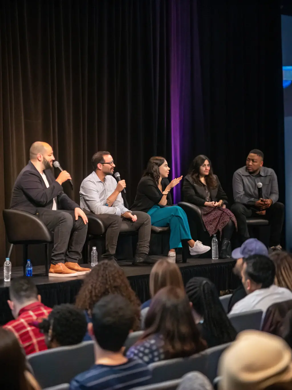 A photograph of a panel discussion at the Entrepreneurs Summit UK, featuring diverse panelists engaging in a lively debate, with audience members attentively listening.